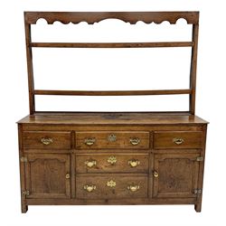 Late 18th century oak dresser, shaped fret work frieze cresting rail over two heights plate rack, the base fitted with four drawers and two cupboards, the central lower drawer is false, stile supports