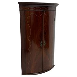 Late Georgian mahogany hanging corner cupboard, moulded cornice with interlaced boxwood stringing pattern above two cupboard doors inlaid with wave form boxwood stringing and four internal shelves 