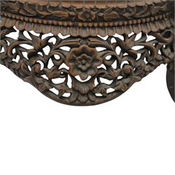 19th century Burmese carved hardwood jardinière stand, circular glazed top over pierced and carved floral frieze, on four zoomorphic supports carved with mythical beast masks and paw feet
