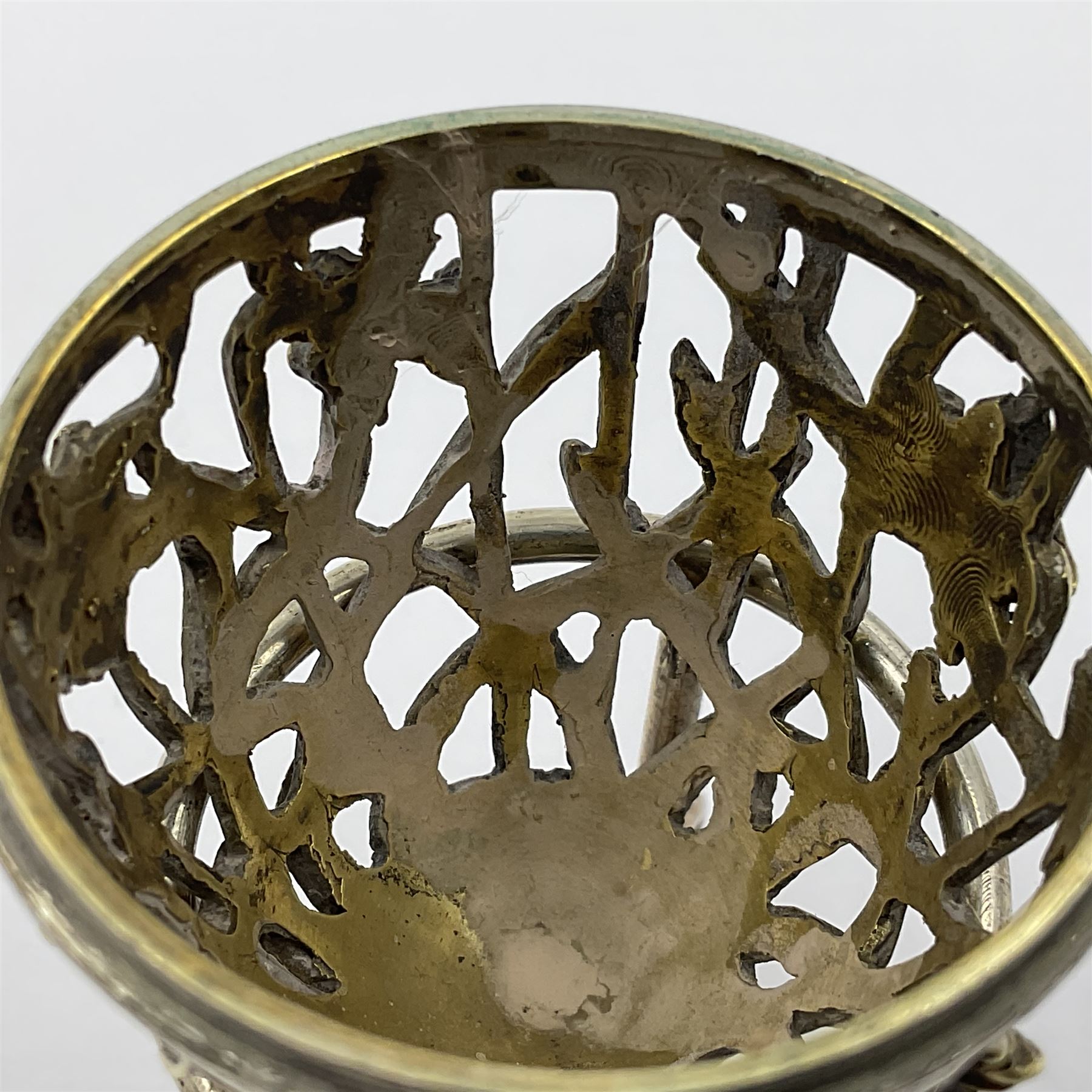 Modern silver limited edition Easter egg, no. 70/500, the gilt openwork body decorated with daffodils and detachable cover with pierced circular panel set with a single faceted blue stone, opening to reveal a gilt interior, upon silver stand with three scrolling pad feet, each hallmarked St James House Company, London 1980, height including stand 8cm