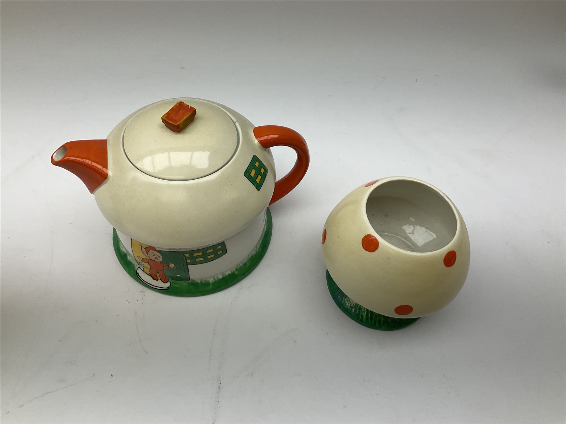 Shelley Boo Boo three piece tea set designed by Mabel Lucie Attwell, comprising teapot modelled as a house, sugar bowl modelled as a toadstool, and creamer modelled as an elf, each with printed marks beneath, together with a Shelley Mabel Lucie Attwell teacup and saucer. 
