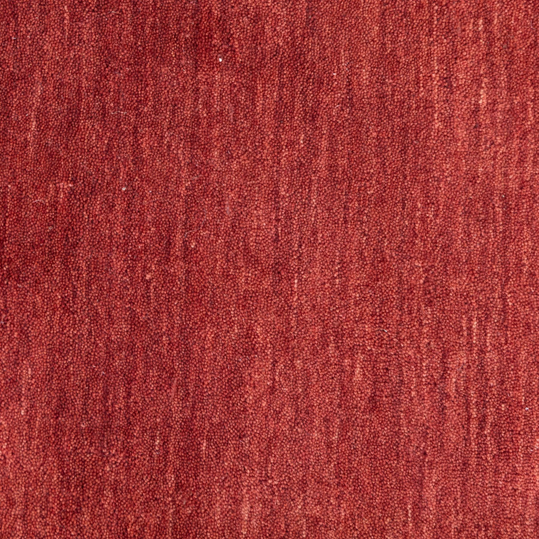Modern Gabbeh red wool rug, plain madder red field with subtle tonal variation and abrash