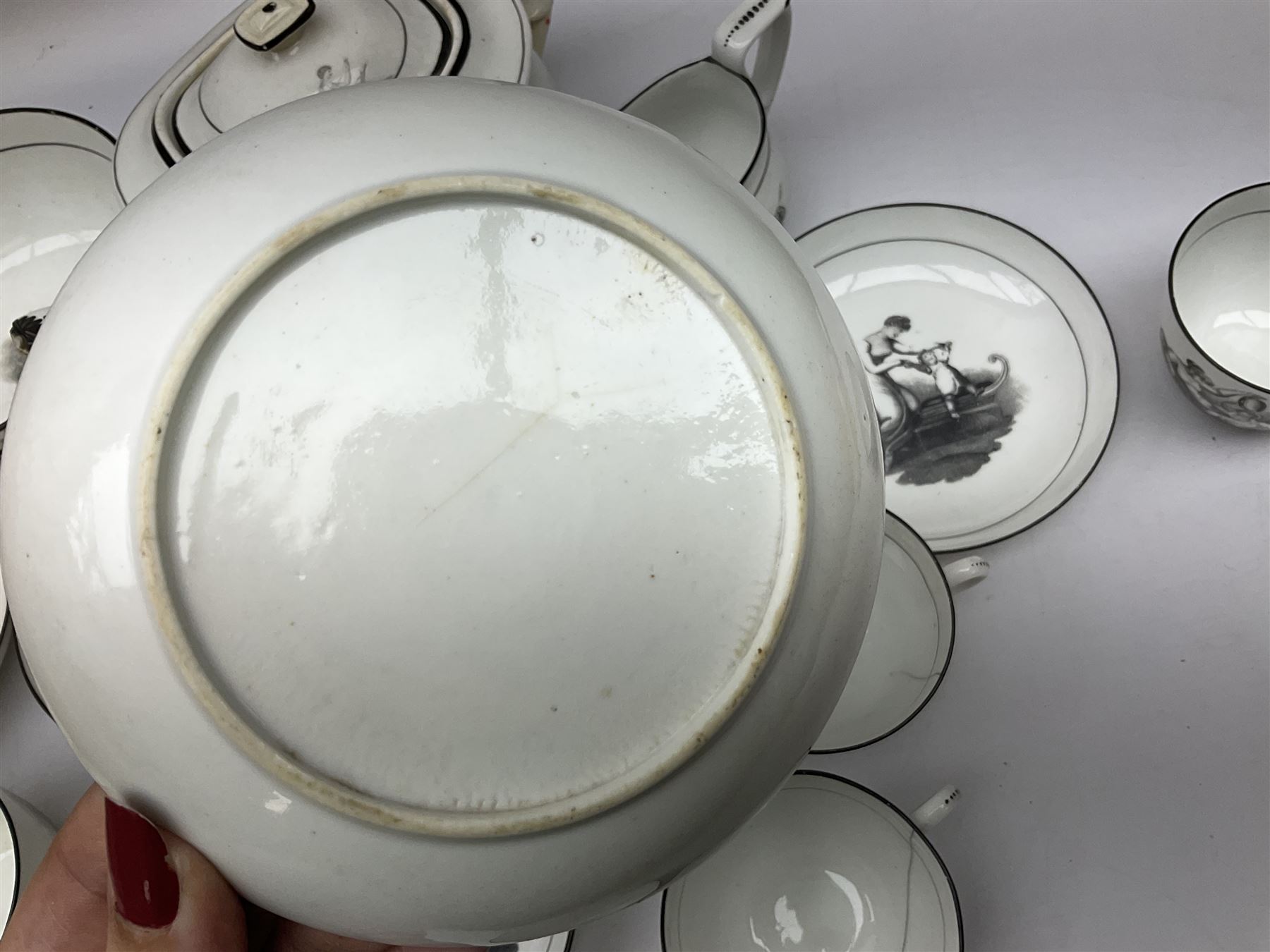 Early 19th century Staffordshire bat printed part tea service, decorated in black after Adam Buck with scenes of mother and child and other varying classical style scenes, within black bands, comprising teapot, slop bowl, jug, seven teacups and five saucers 