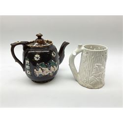 A 19th century Barge Ware teapot, decorated with applied floral sprays and thistles against a mottled brown ground, and plaque detailed Catherine Taylor God Bless Our Home 1890, H18cm, together with a white glazed puzzle mug, H15cm. 
