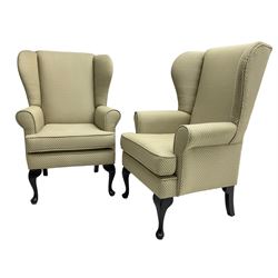 Pair of Queen Anne design wingback armchairs, traditional shape with rolled arms, upholstered in fan patterned fabric, raised on ebonised cabriole supports