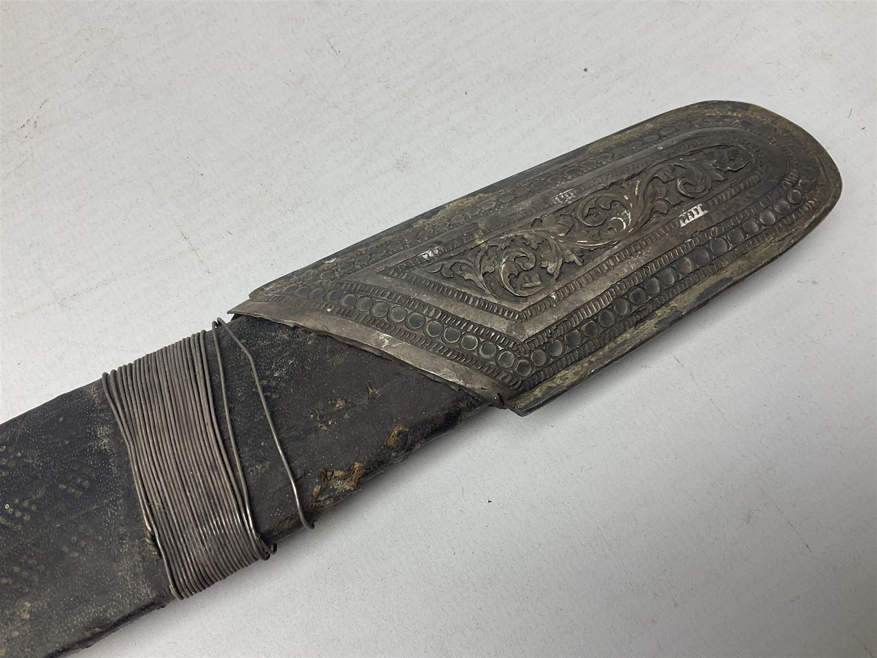 Omani presentation sword kattara, with 77cm  broad slightly curved single edge blade with two fullers, leather bound hilt woven with silver wire decoration and iron pommel;  in tooled leather scabbard with chased silver mounts and presentation plaque 'To Capt. D.M. Naylor From C Company NFR Oman Dec 1962' (Northern Frontier Regiment) L99cm overall