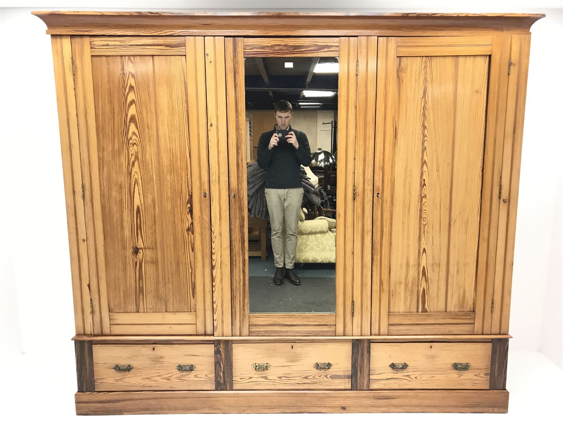 Late Victorian large pitch pine triple wardrobe, projecting cornice, central mirrored door flanked by two others above three drawers, plinth base