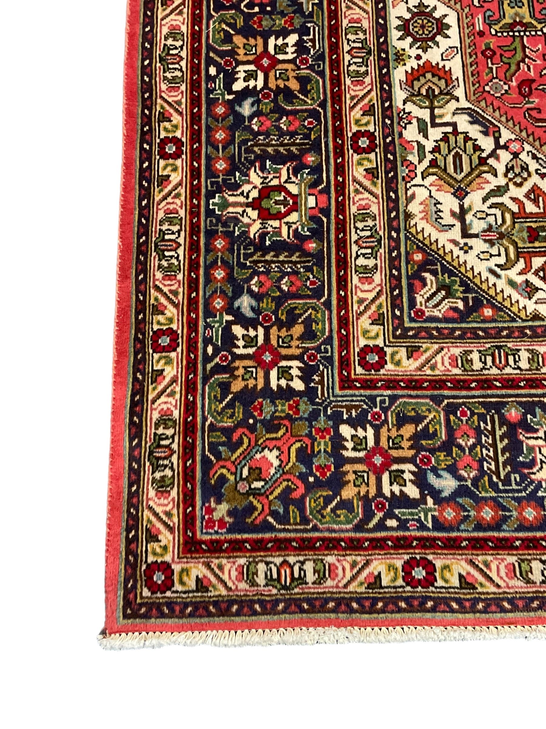 North West Persian pink ground Tabriz carpet, central indigo ground medallion surrounded by stylised plant motifs and trailing foliage, the main border with overall floral design within guard stripes 