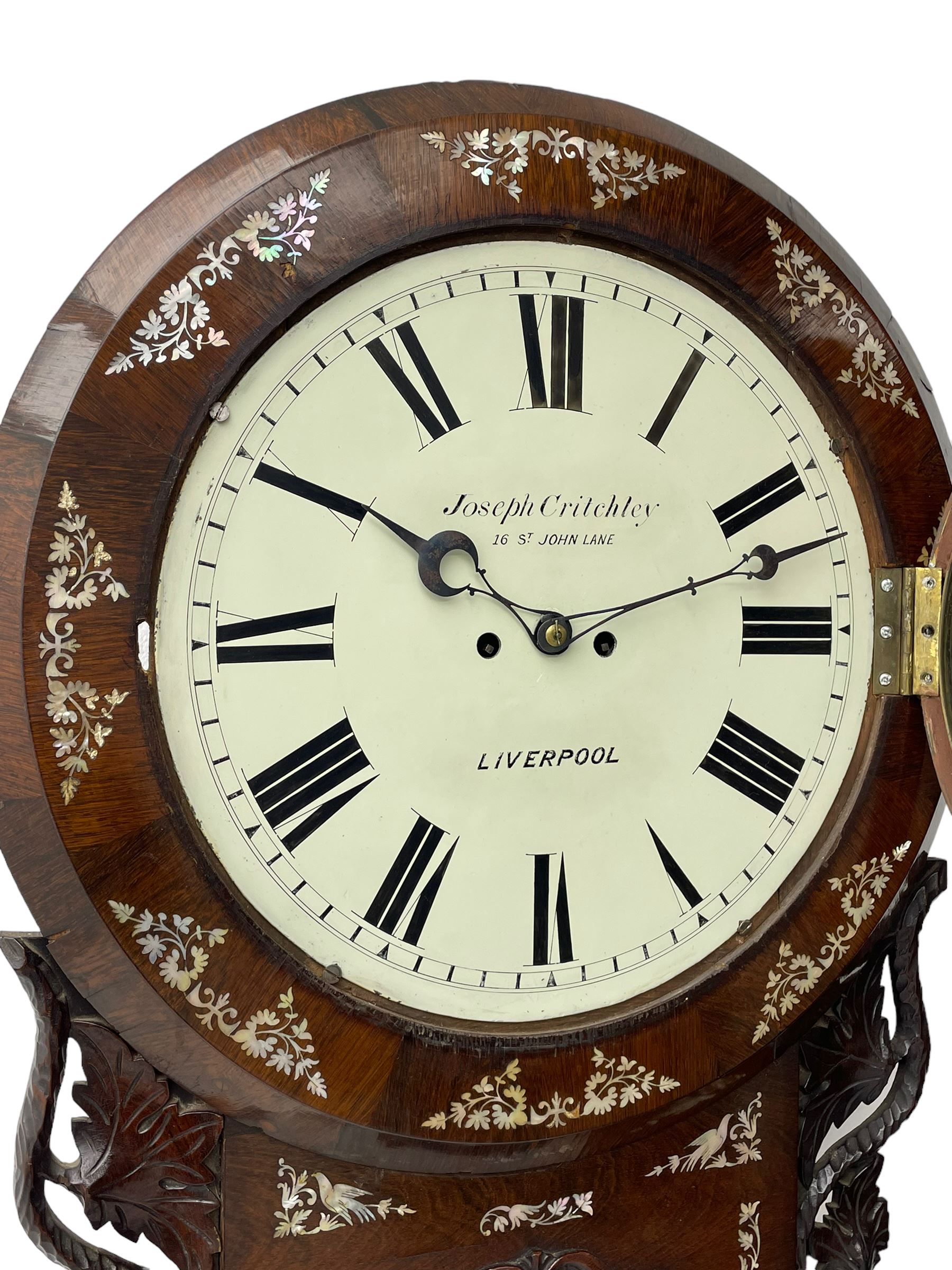 Joseph Critchley of Liverpool -  early 19th century twin fusee 8-day rosewood and mother of pearl inlaid drop-dial wall clock c1820, inlaid circular wooden dial surround with carved ears representing grapes and vine leaves, glazed box with a scroll carved surround, curved base and pendulum adjustment door, 14” painted dial with Roman numerals, minute track, and pierced steel hands within a cast brass bezel and flat glass, dial pinned to a four pillar chain driven fusee movement striking the hours on a bell. With pendulum and key.