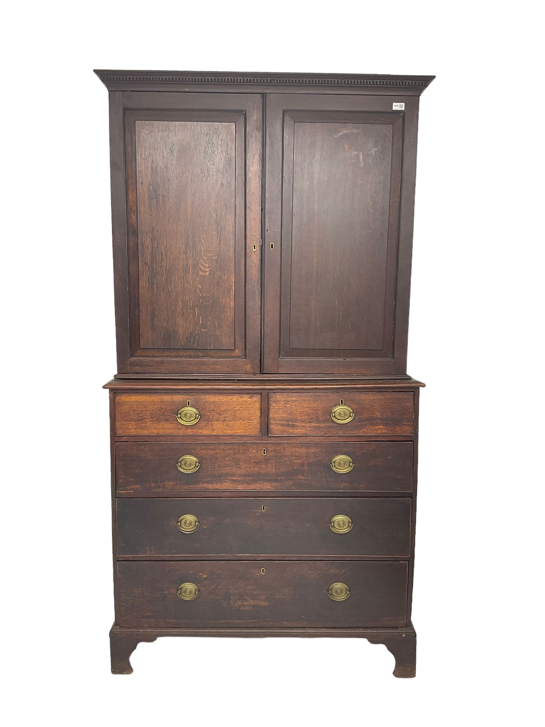 George III oak linen press, projecting cornice with dentil moulding over two panelled doors enclosing two adjustable shelves, fitted with two short over three long drawers, raised on bracket feet