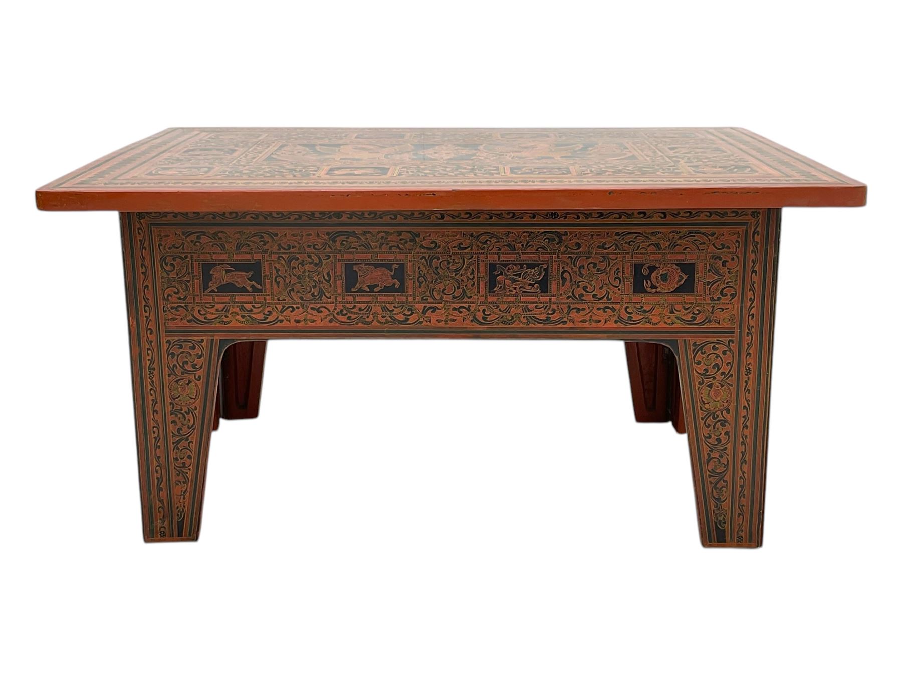 Late 20th century Burmese low table, the rectangular top and frieze decorated in traditional Shwezawa lacquer with gilded celestial figures, mythological beasts and dense foliate scrollwork, the folding base with hinged slab supports bearing conforming decoration
