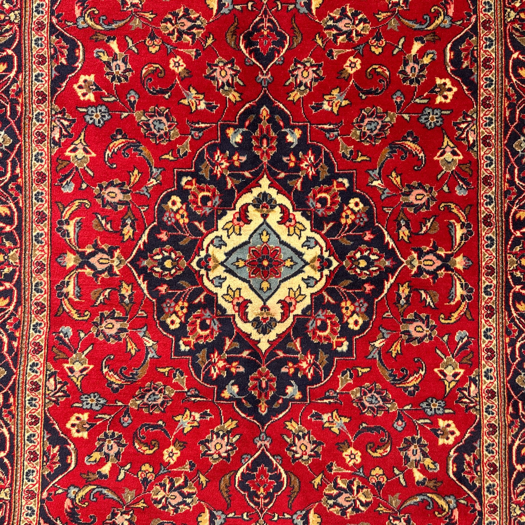 Central Persian Kashan rug, crimson ground with central medallion with  quarter medallions in each corner and decorated with floral sprays and palmettes, dark blue main border with repeating palmette and vine pattern   framed by small guard border with floral meanders 
