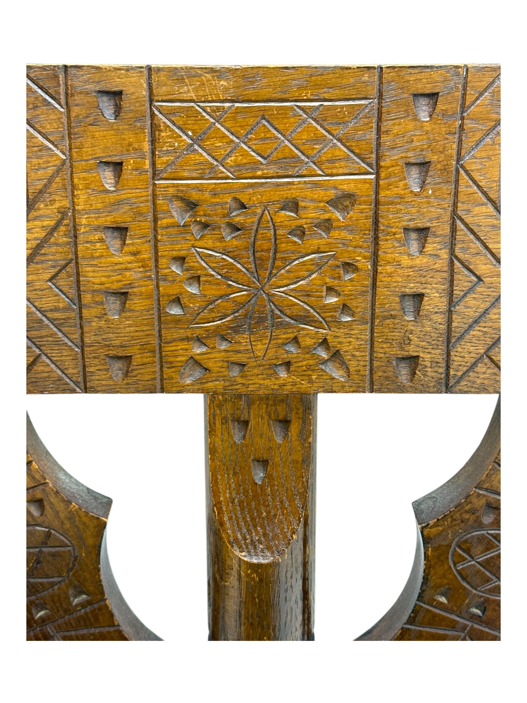 19th century swedish monk's chair, the oak frame with triangular seat and sloped arms, the backrest carved with geometric chipwork and a central pierced medallion 