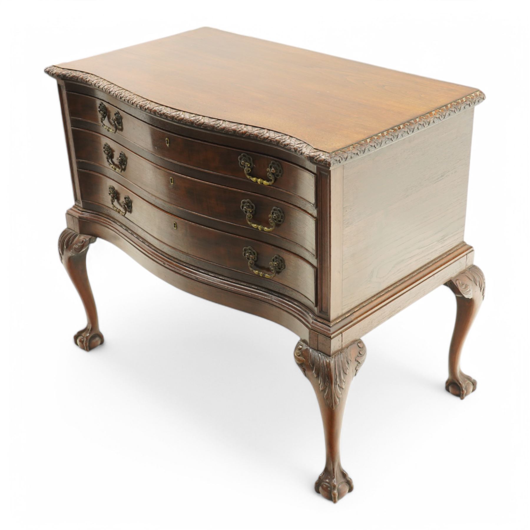 20th century oak and mahogany serpentine chest, the moulded top carved with trailing crossed ribbon and flower heads, fitted with three long cock-beaded drawers, ornate cast gilt metal handles, on acanthus leaf carved cabriole supports with ball and claw feet 
