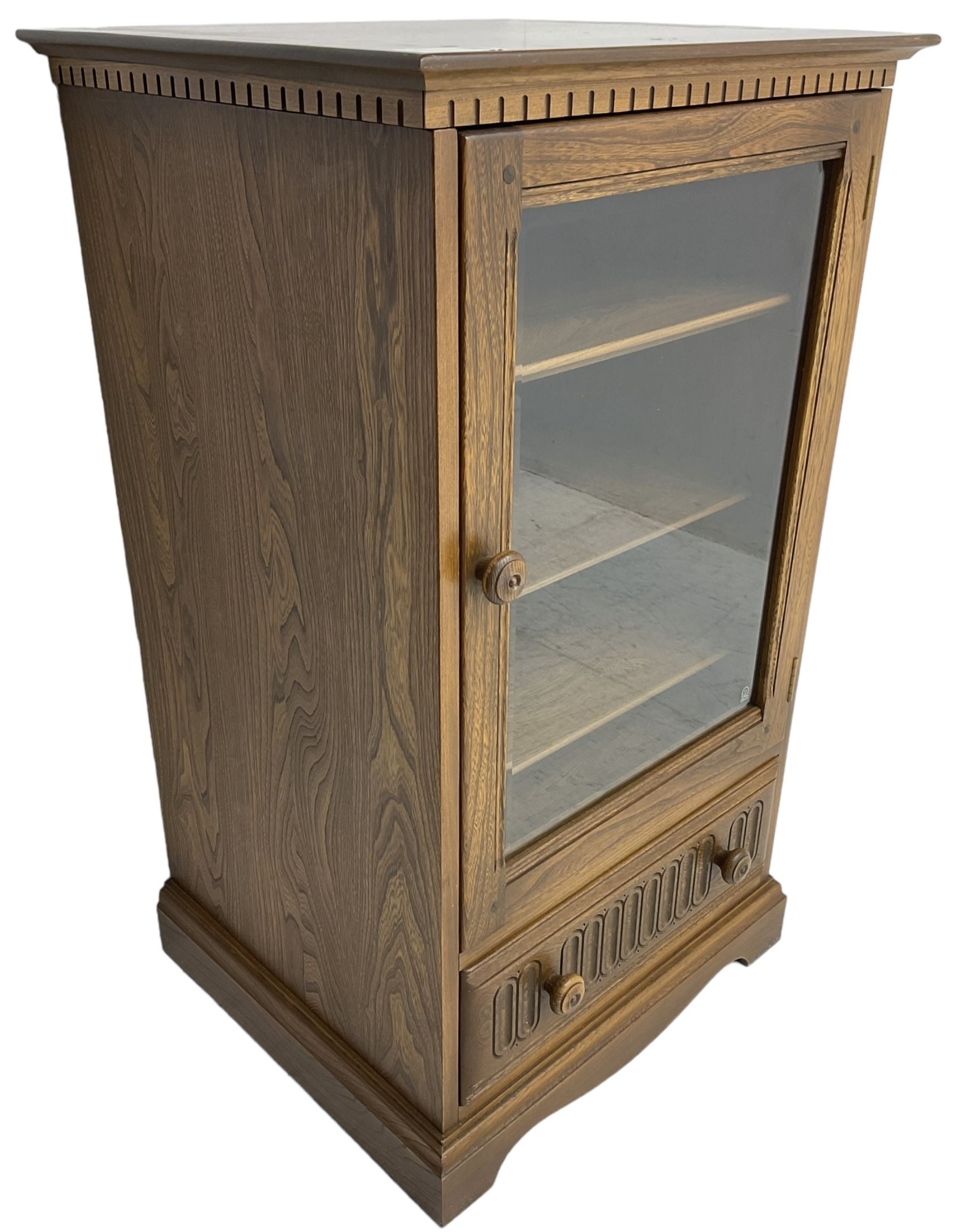 Ercol - mid-20th century dark elm 'Old Colonial' music cabinet, single glazed door enclosing three shelves, single drawer fitted to base