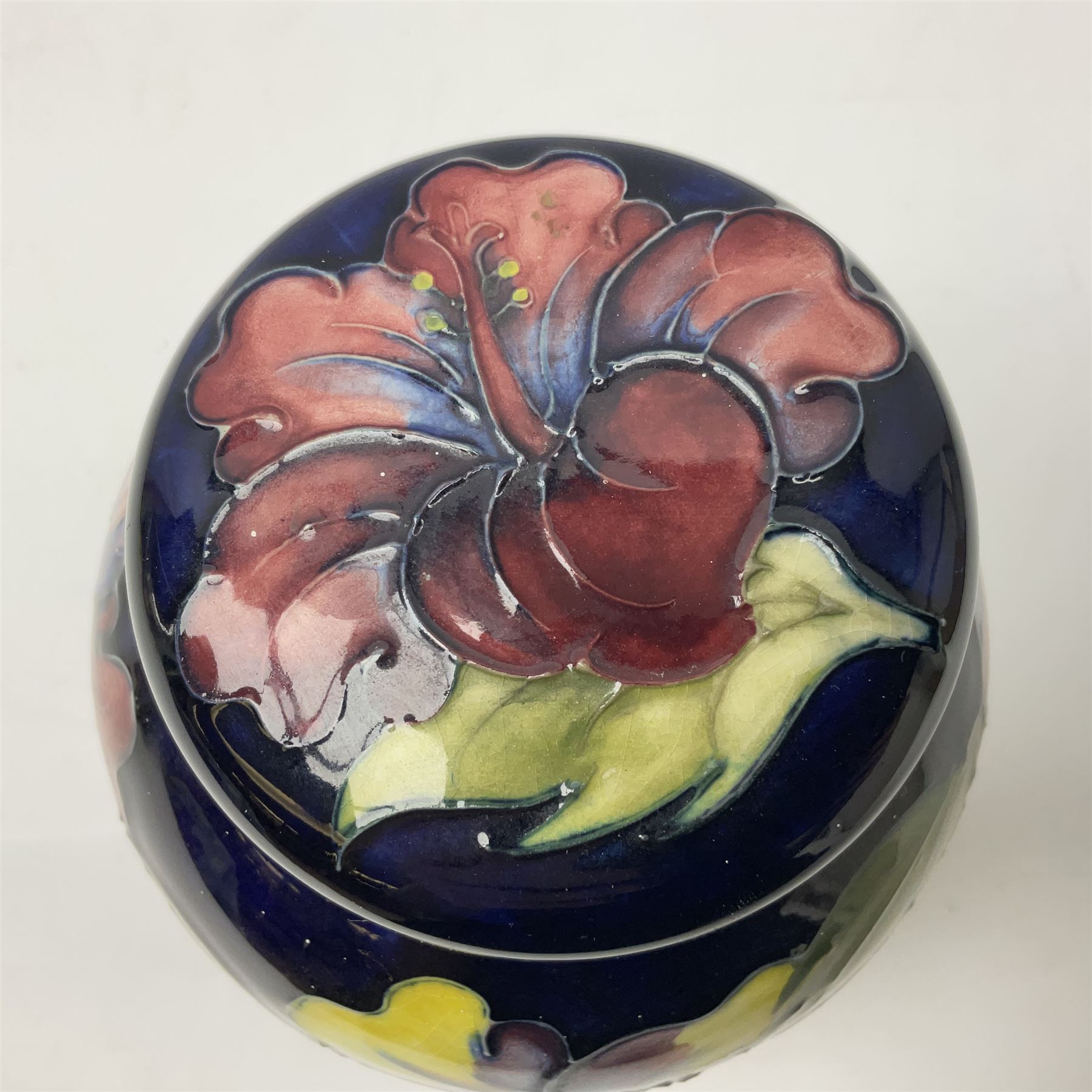Moorcroft ginger jar, decorated in the Hibiscus pattern upon a cobalt blue ground,  with impressed Moorcroft, Made in England marks beneath and paper label detailed Potters to the late Queen Mary, H15cm