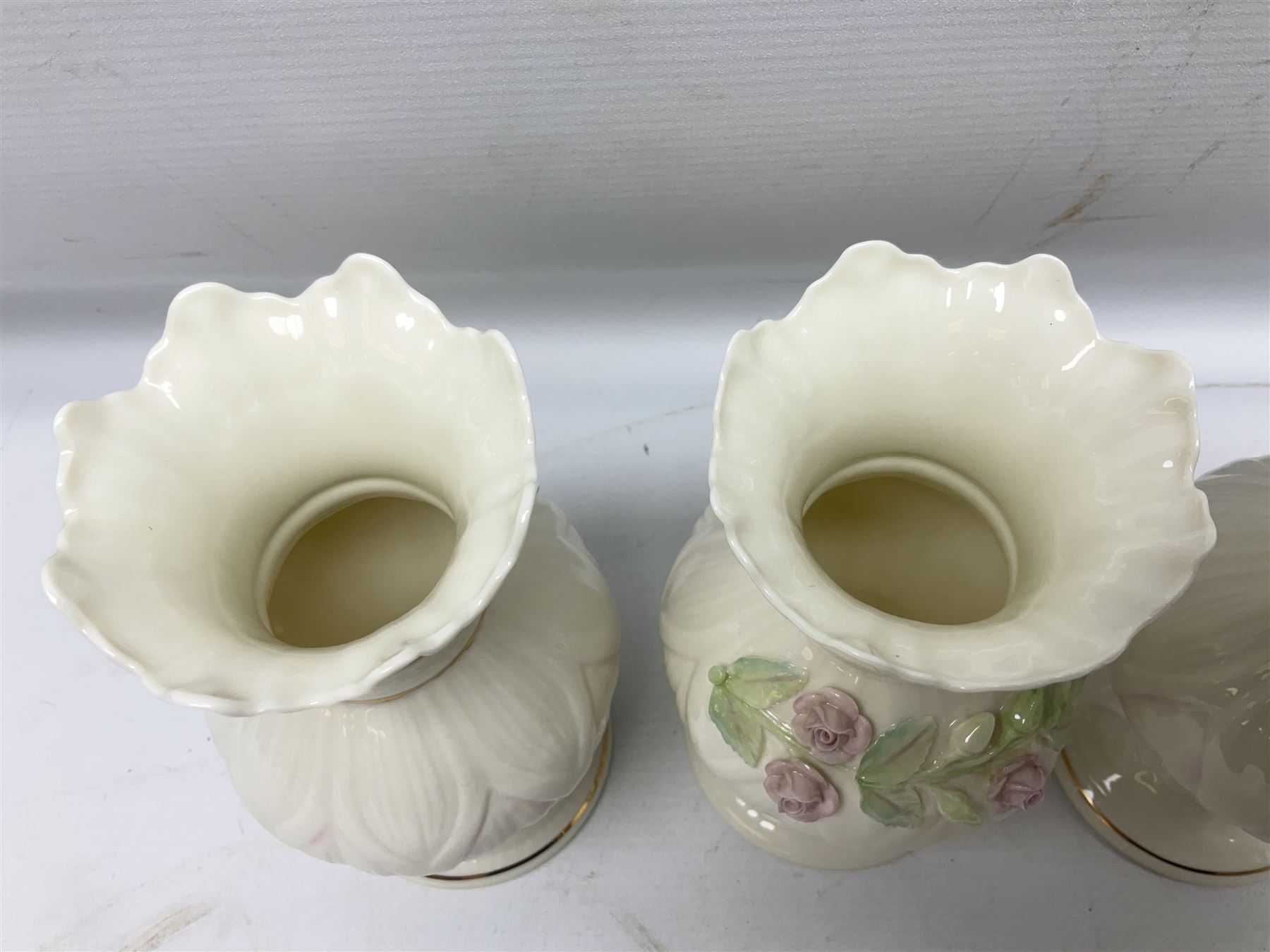 Five late 19th/early 20th century and later Belleek vases, comprising pair of Lotus Blossom examples, shamrock tree trunk vase, twin handled shamrock vase and a baluster form vase decorated with applied roses, all with printed marks beneath, tallest H16cm