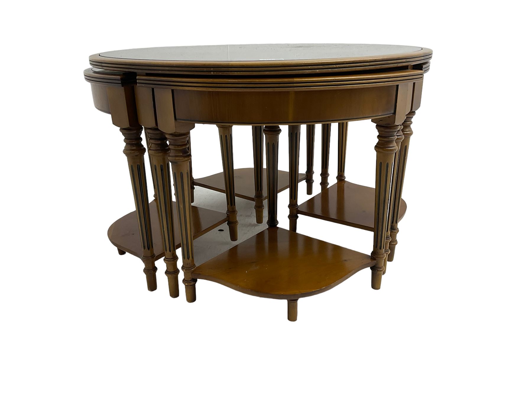 Yew wood circular coffee table with four nesting tables, inset leather and glass tops, on turned and fluted supports