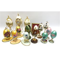 Fifteen decorative eggs, including a garniture with central example set with clock, three examples painted with flowers upon a yellow ground, one example opening to reveal a bird within, etc. 
