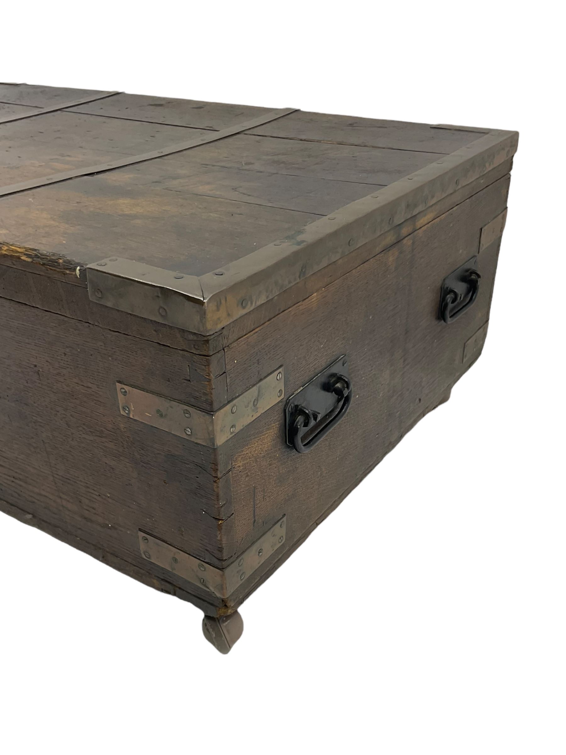 Early 19th century oak low blanket chest, metal strapped and bound, two carrying handles to either end, on castors