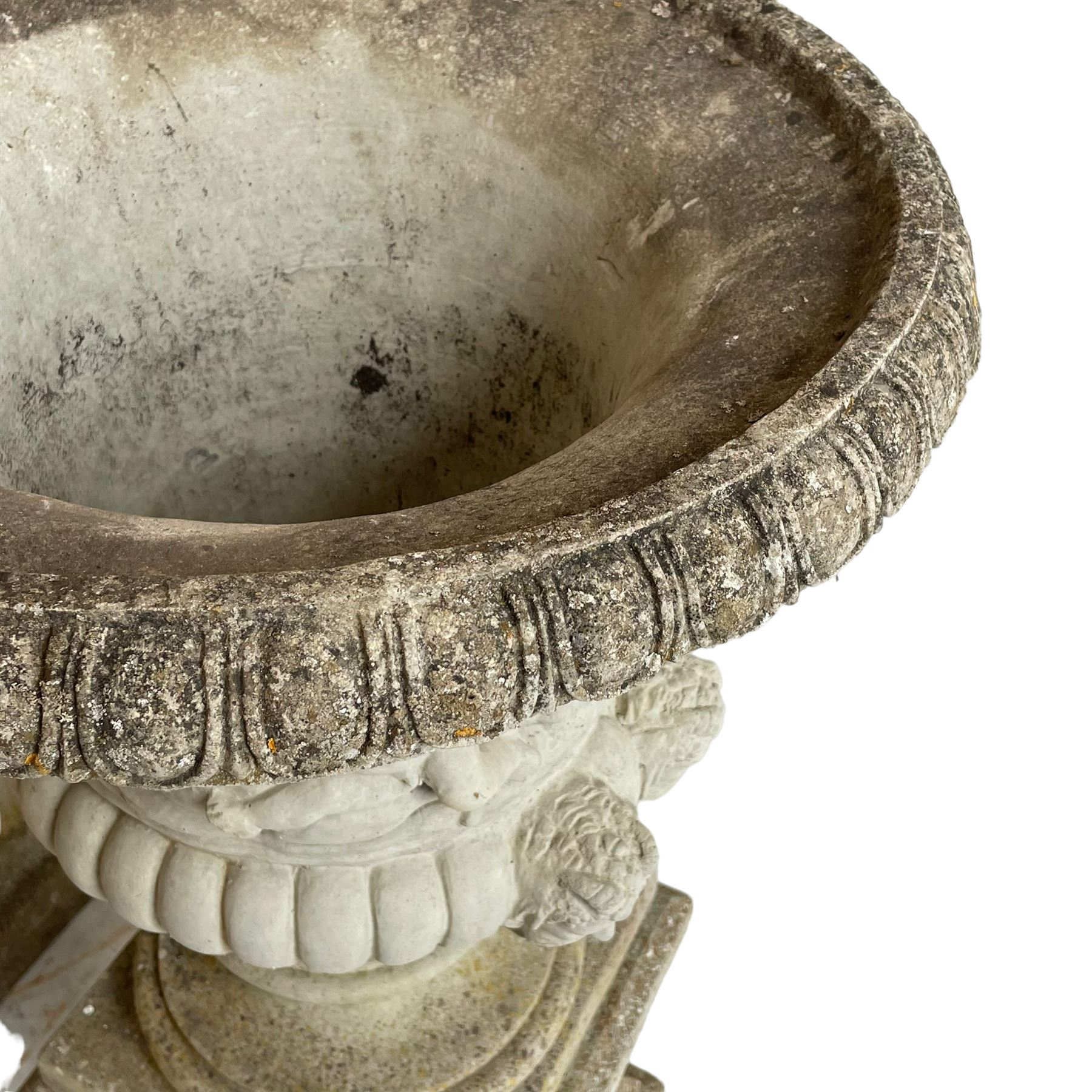 Large pair of cast stone three-piece Grecian urns, the moulded rim over body decorated with putti, horses and trees, gadrooned underbelly with faun masks, on stepped and moulded circular footed base, the square plinth with moulded upper edge, each side decorated with laurel wreath, moulded skirted base