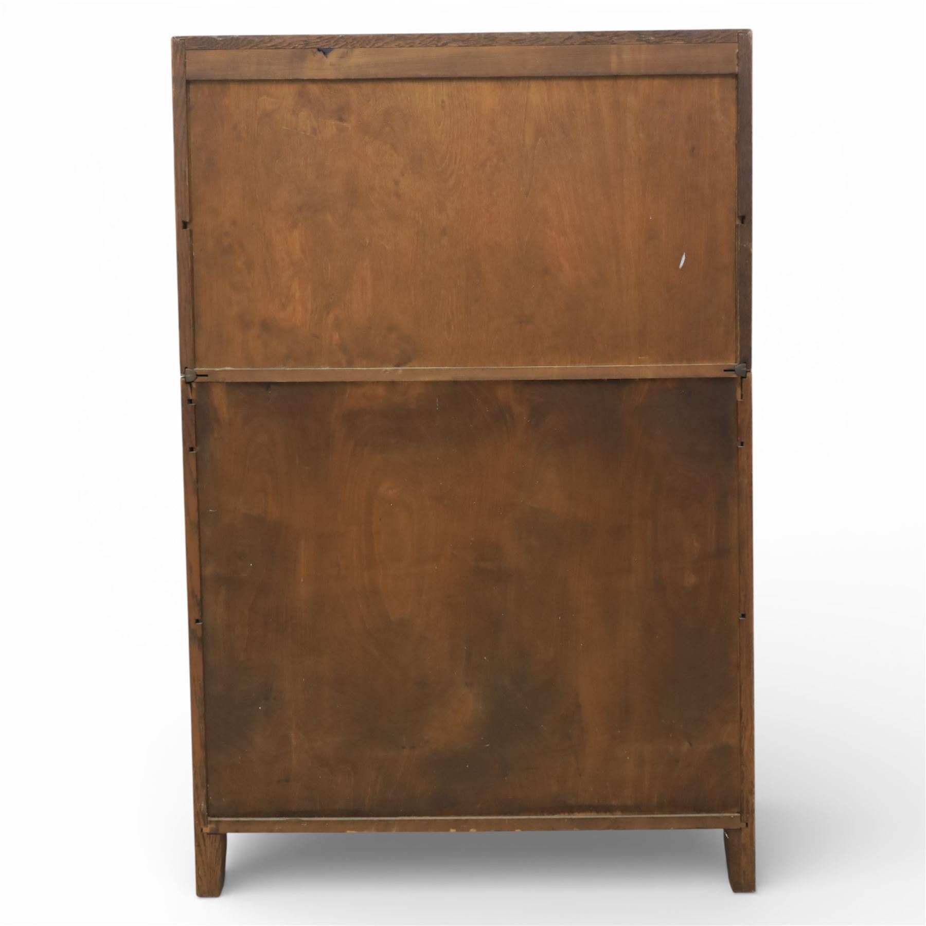 Early 20th-century Arts and Crafts glazed oak bookcase, upper section fitted with a pair of leaded glazed doors enclosing a fixed shelf above a projecting frieze drawer interior with baize-lined writing surface flanked by two compartments, carved with interlaced decoration, lower section fitted with a further pair of leaded glazed doors enclosing a single shelf, raised on short stile feet 