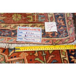 North West Persian Karajeh hand-knotted runner, field decorted with a series of linked stepped hexagonal medallions encloing stylized geometric motifs, surround by angular floral and tribal devices on a terracotta red ground enclosed a navy main border of repeating geometric and rosette motifs, between multiple guard stripes, with cotton fringe ends 