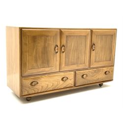 Ercol sideboard, fitted with three cupboards enclosing shelving above two long drawers to the base, raised on castors 