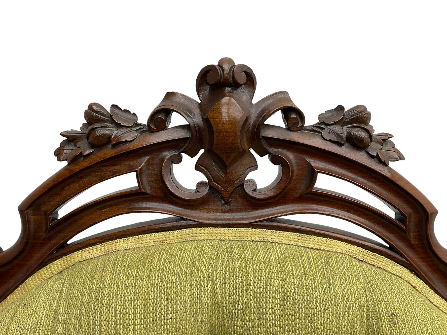 Victorian walnut settee, triple back with pierced and scroll-carved cresting rails over carved fruit and foliage decoration, upholstered in buttoned green fabric, serpentine seat and carved apron, on cabriole feet
