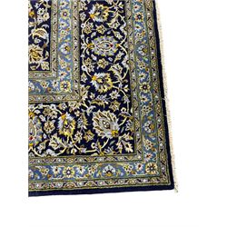 Central Persian Kashan indigo ground carpet, central lighter blue floral medallion surrounded by interlacing leafy branches and stylised plant motifs, the main border decorated with repeating floral motifs and scrolling branches, within guard stripes 
