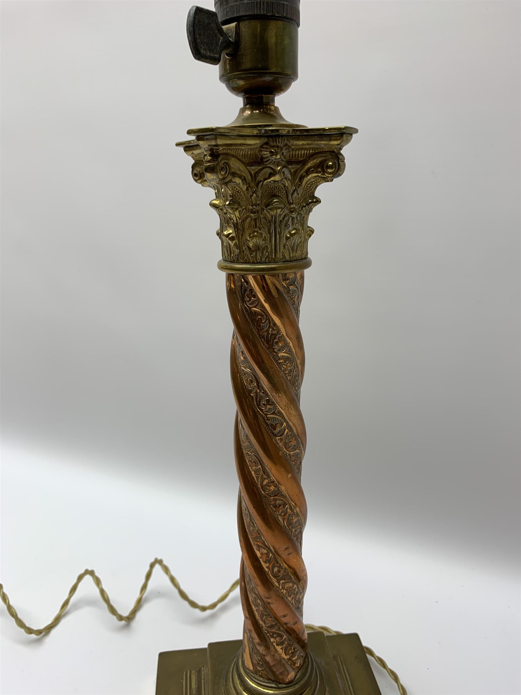 Early 20th century brass and copper Corinthian column table lamp, the square stepped brass base leading to a spiral twist copper column and brass Corinthian capital, H44.5cm 