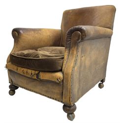 Early 20th century club armchair, upholstered in tan leather with upholstered seat cushion in brown fabric, rolled arms, on turned front feet with castors 