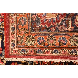  Meshed multicoloured carpet, red field with central floral medallion centre and spandrels with repeating striped border, 377cm x 300cm  