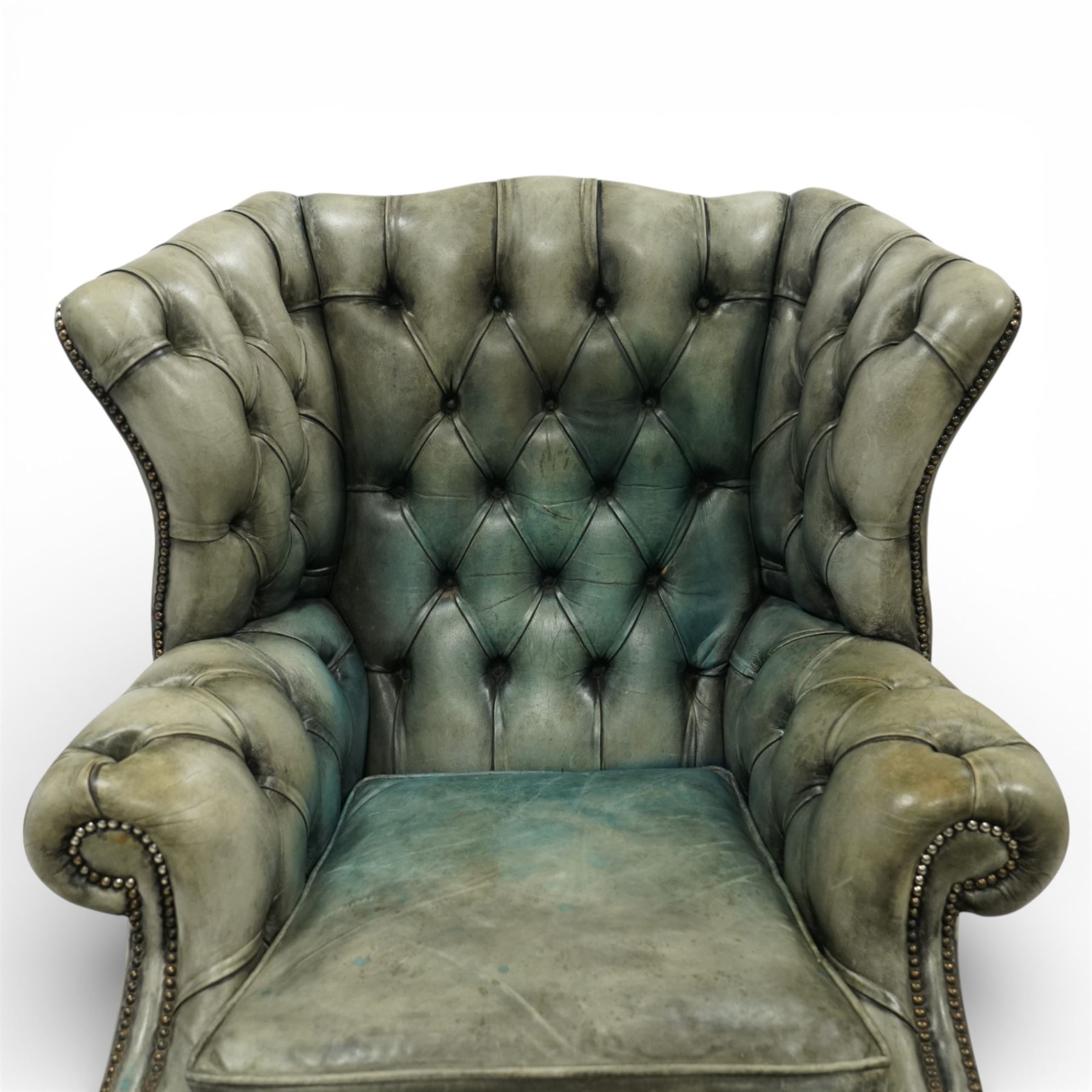 Georgian design mahogany framed wingback armchair, upholstered in rustic pale green buttoned leather with loose seat cushion, raised on square supports united by H-stretcher