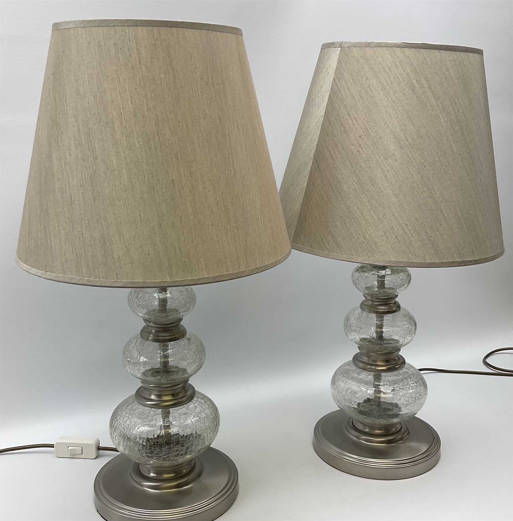 A pair of crackle glass table lamps each of three spheres, on circular
