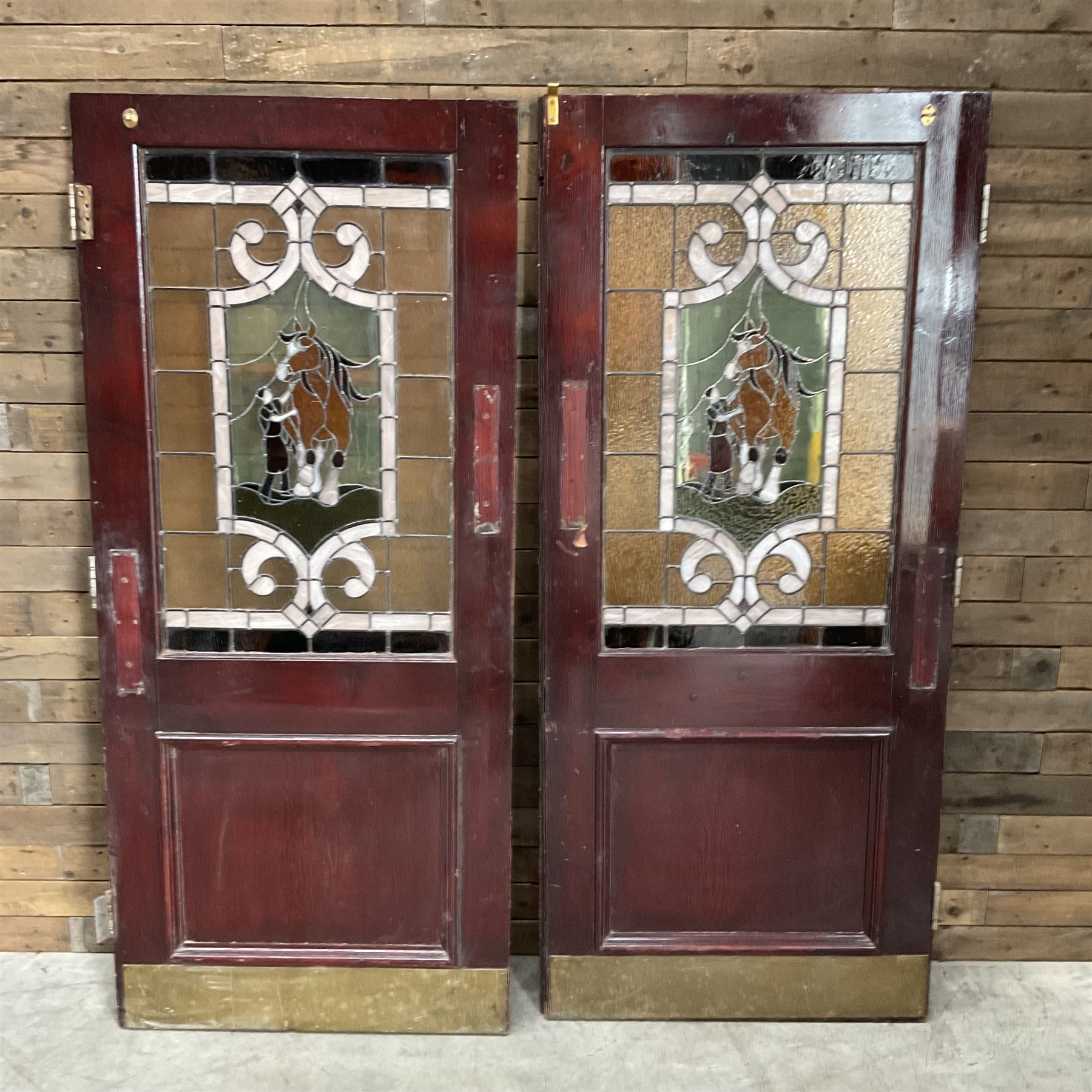 Two early to mid 20th century timber doors, set with lead framed stained glass panels depicting agricultural worker and horse