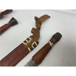 Indian kukri with 29cm curving steel blade and nickel mounted horn grip; in leather covered scabbard with one skinning knife L42cm overall; Hitler Youth knife with scabbard in relic condition; and three African graduated knives each with crudely carved wooden grips and painted leather covered scabbards (5)