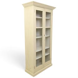 Traditional white painted pine display cabinet, projecting cornice above two glazed doors enclosing five fixed shelves, tongue and groove back raised on a plinth base