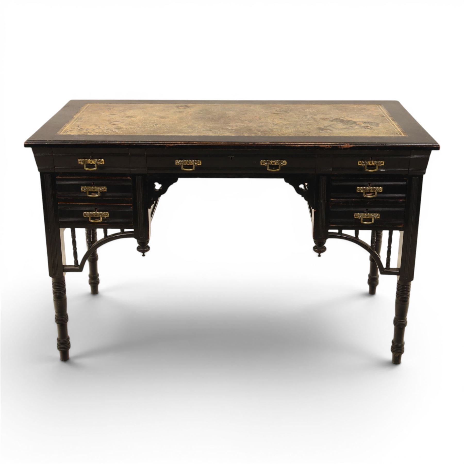 Victorian Aesthetic Movement ebonised writing desk, rectangular top with inset tooled leather, central frieze drawer with pierced spandrels, flanked by two banks of three drawers, brass swing handles, raised on turned supports 