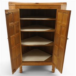 Mouseman - 1940's adzed and panelled oak corner cupboard, the raised quarter-gallery back over twin adzed panelled doors with wrought iron fittings and latch, enclosing three shaped shelves, raised on turned octagonal supports, with carved mouse signature in relief, by the workshop of Robert Thompson of Kilburn Provenance: purchased directly from the Kilburn workshop in the late 1940s