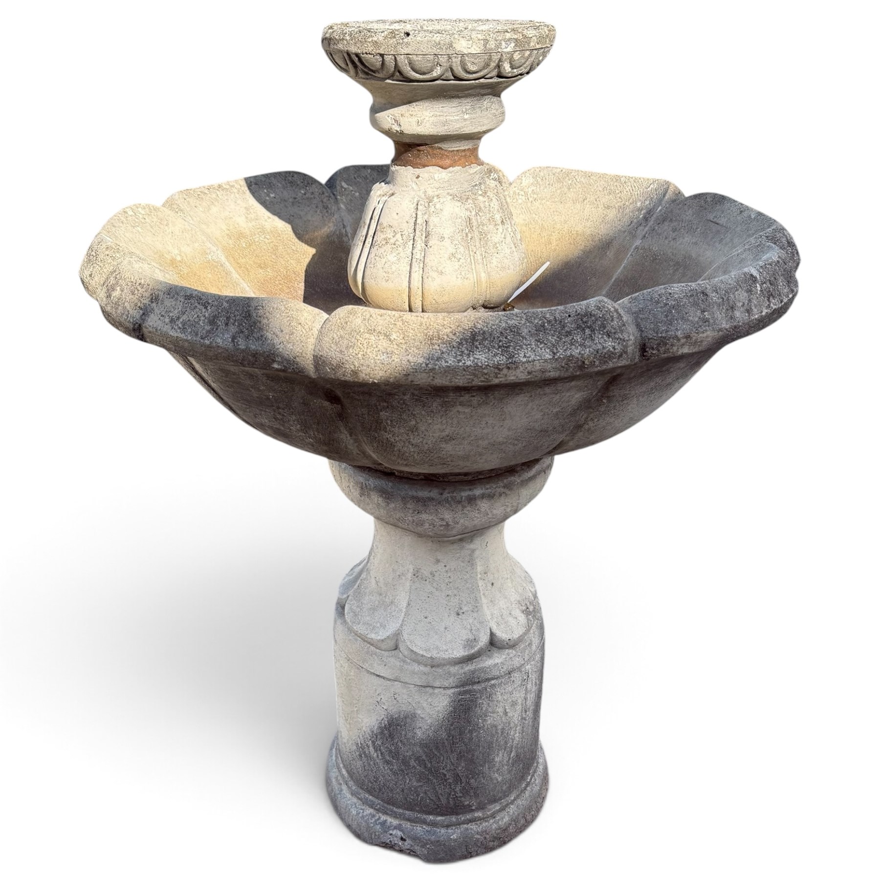 Weathered cast stone garden water feature fountain, the raised central spout with egg-and-dart moulding, within a scalloped basin raised on a lappet pedestal with cylindrical plinth base