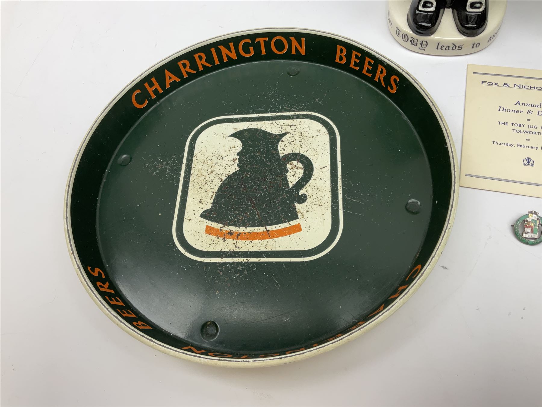 Pair of Royal Doulton Toby Ale Jugs, produced in 1934 for Charrington Ales, together with two circular metal serving trays advertising Charrington brewery, a Charrington badge awarded for 25 years of service and a 1949 menu Fox & Nicholl Ltd annual dinner dance at the toby jug hotel.  