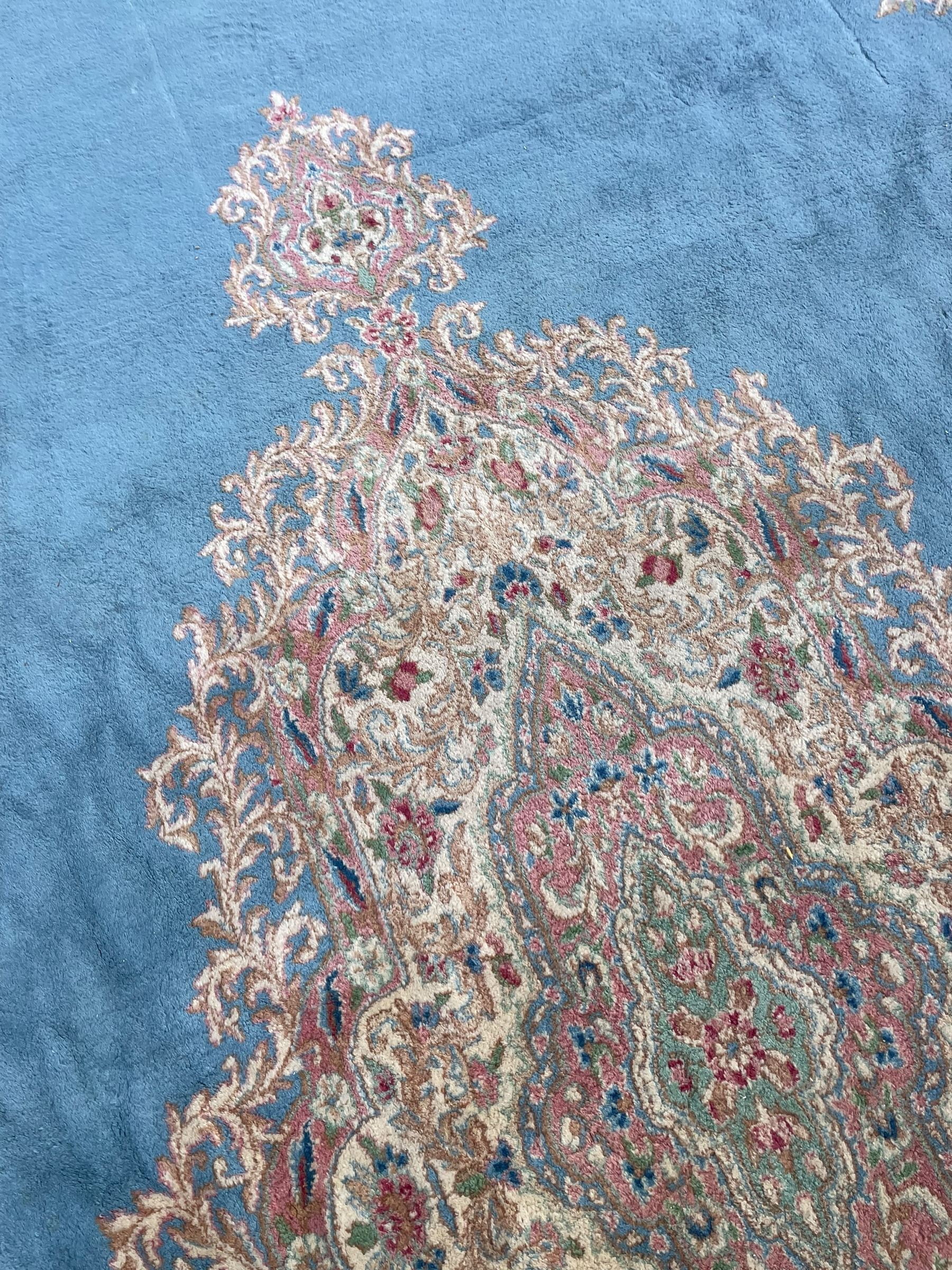 Large Persian design carpet, plain light blue field with floral design central medallion, scrolling foliate spandrels and borders decorated with flower heads