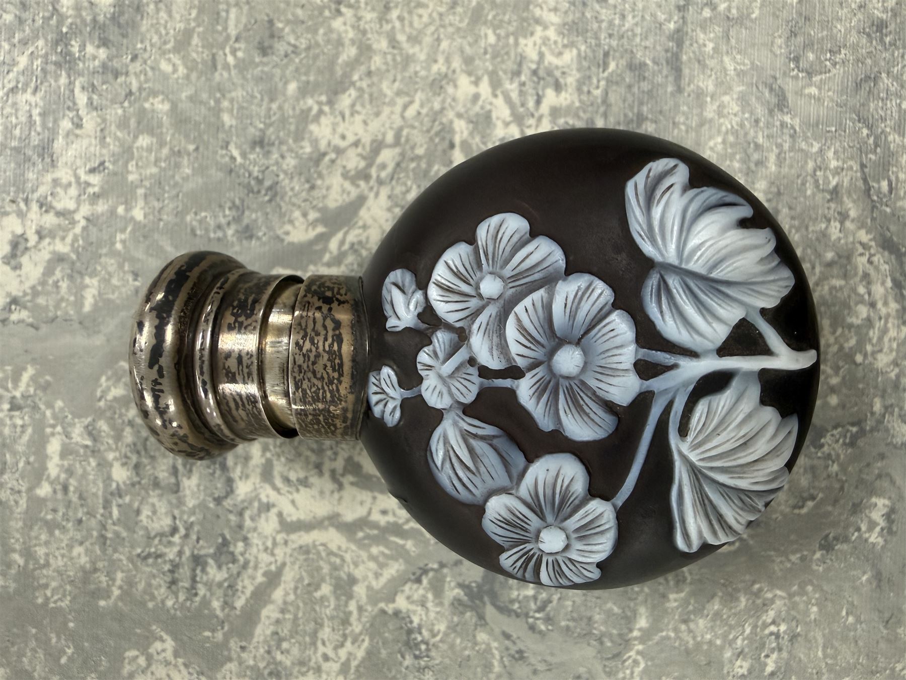 Victorian Thomas Webb silver mounted cameo glass scent bottle, hallmarked Sampson Mordan and Co, London 1884, the cameo glass body of circular form, decorated with white flowers and foliage in high relief upon a black ground, the hinged cover opening to reveal the original stopper, H6cm 