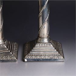 Pair of Edwardian silver mounted column candlesticks, each with embossed floral, foliate and scrolling decoration and upon stepped square weighted bases, hallmarked William Hutton & Sons Ltd, London 1901, H19cm