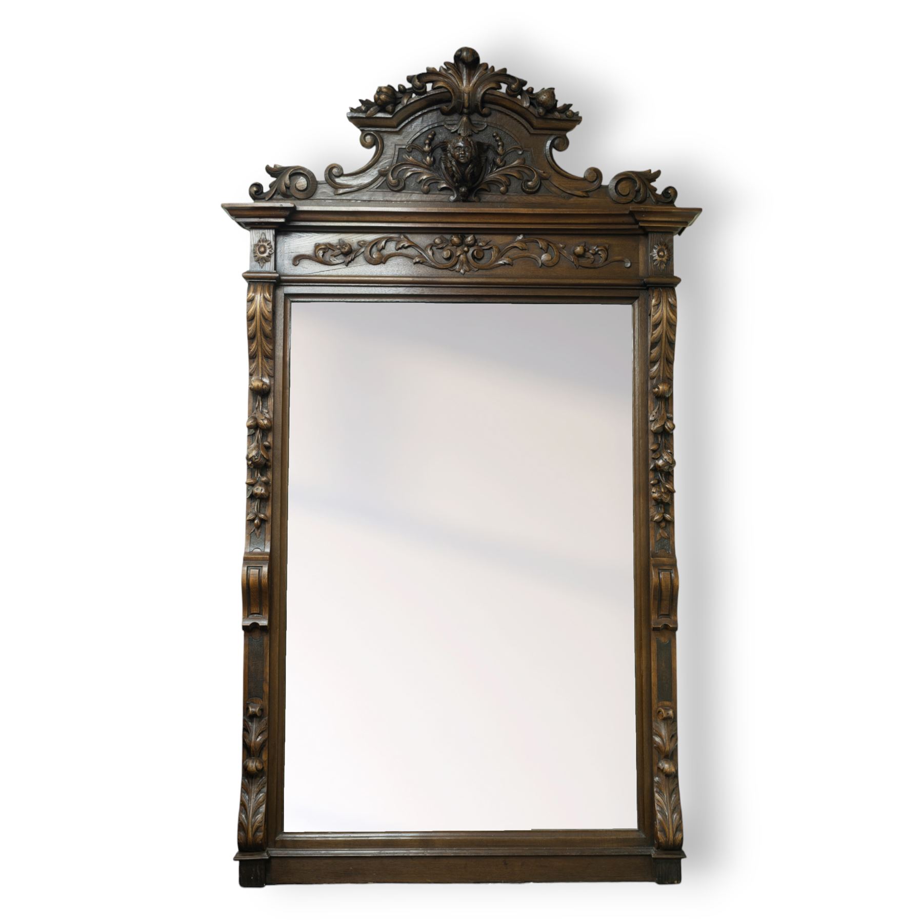 Large mid-19th-century Victorian rococo revival carved oak overmantel mirror, the rectangular mirror frame carved in high relief,  arched and scrolled pediment surmounted by a central foliate spray with acanthus scrolls above a finely carved classical mask, frieze decorated with symmetrical  acanthus scrolling, vertical uprights carved with trailing foliage, flowers, and ribbon-tied elements, terminating on a square supports 