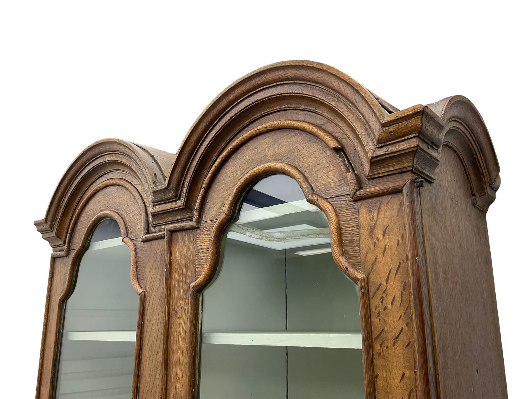 George III oak bookcase on bureau, the double arched top enclosed by two shaped glazed doors, fall-front concealing fitted interior, over four graduating cock-beaded drawers, on bracket feet