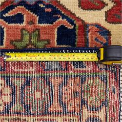 North West Persian Karajeh hand-knotted runner, madder red field, decorated with a vertical sequence of bold geometric medallions, interspersed with stylized floral and tribal motifs, framed by a dark ground border of angular palmettes and rosettes with multiple guard stripes, with cotton fringe ends 