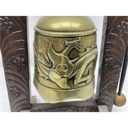 Chinese brass temple bell, decorated in high relief with a a dragon chasing a flaming pearl, within a carved floral hardwood stand, H36cm