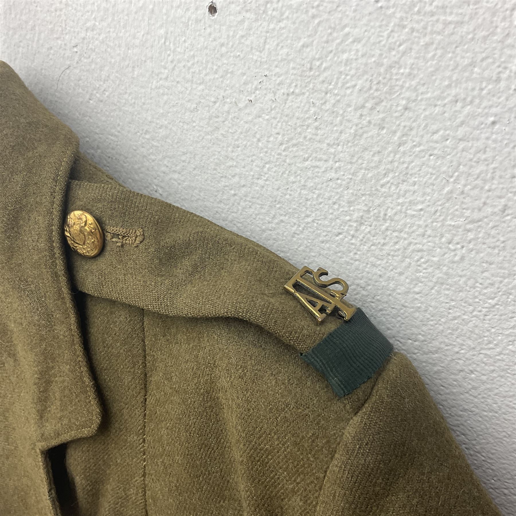 WW2 British female ATS Sergeant's service uniform grouping, consisting of four pocket female pattern service dress tunic with brass ATS shoulder titles and general service buttons; cloth lined interior with the original printed size label dated 1942; the matching khaki service dress skirt; and Greatcoat with size label dated 1945; together with army knitted sleeveless V-neck jumper; WRAC tunic, skirt and overcoat; full length cream and gold thread military evening dress by Hilliers Couture; and four webbing belts